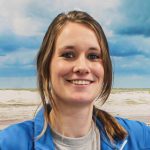 Frau mit blonden Haaren und blauem Jackett lächelt in die Kamera.