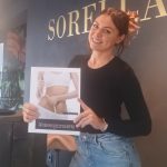 Frau hält Broschüre mit Abbildung einer schlanken Taille und der Aufschrift "Afslankingsconsulente" (Schlankheitsberaterin).