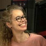 Lachende Frau mit Brille im Fitnessstudio, bereit für gesunde Ernährung.